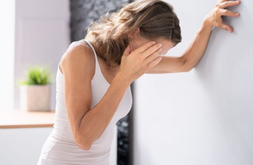 Woman leaning against the wall, touching her head in exhaustion