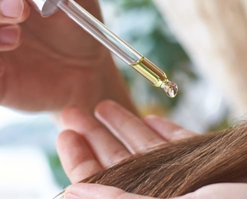 Öl tropft auf eine lange Haarsträhne