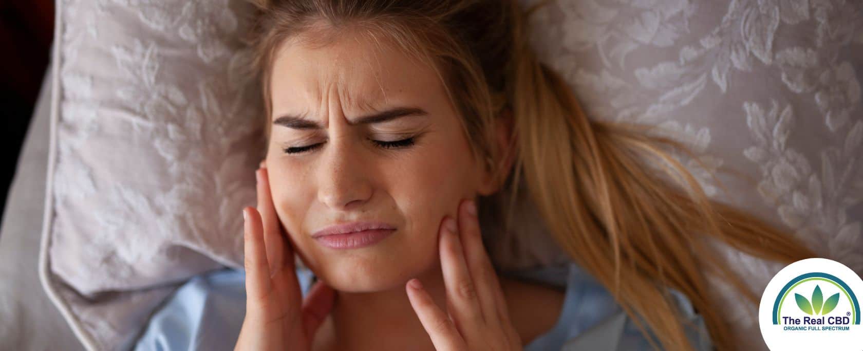 Woman holding her cheeks in pain after teeth grinding