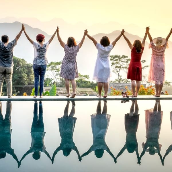 A row of happy people standing celebrating life on the edge of a pool