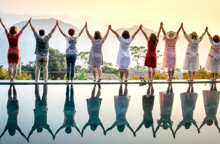 A row of happy people standing celebrating life on the edge of a pool