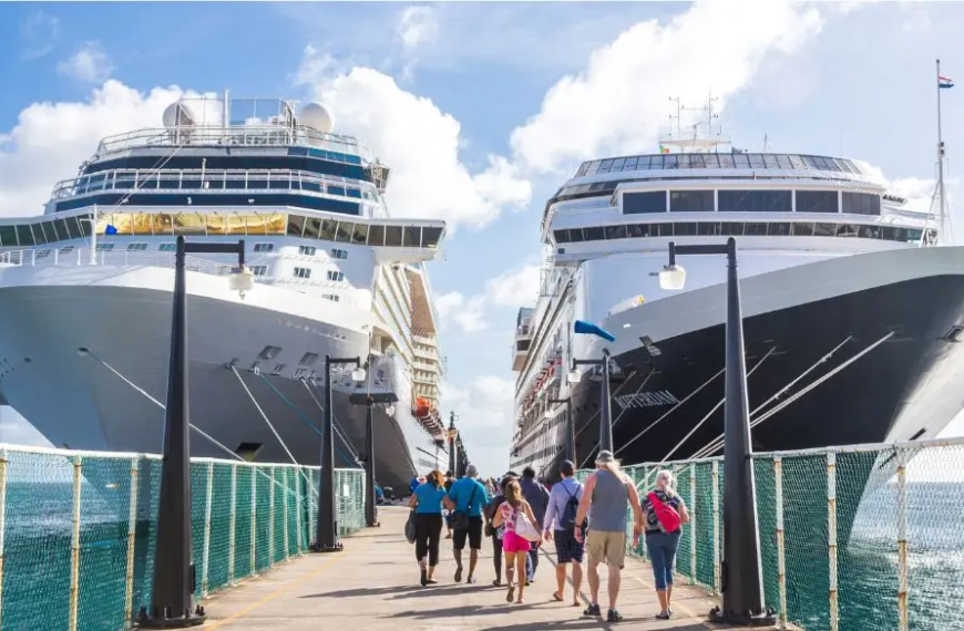 Twee grote cruiseschepen met toeristen die erheen lopen