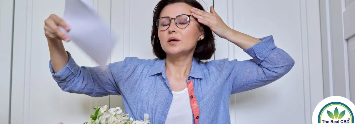 Vrouw met een opvlieger, die zichzelf afkoelt met een papiertje