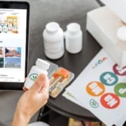 The-Real-CBD-blog-Ist-CBD-ein-Biohack Ein Mann hält ein Tablet mit der The Real CBD Website und ein Glas mit The Real CBD Tabletten
