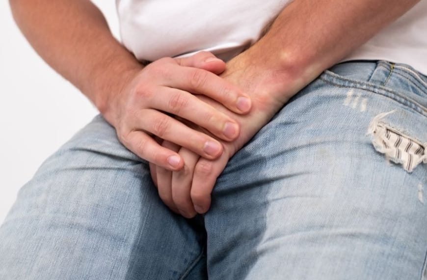 Man maakt zichzelf nat terwijl hij zijn kruis vasthoudt