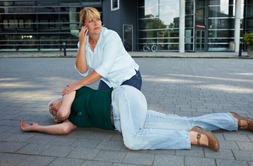 Woman calling for help for a person on the ground having a seizuer
