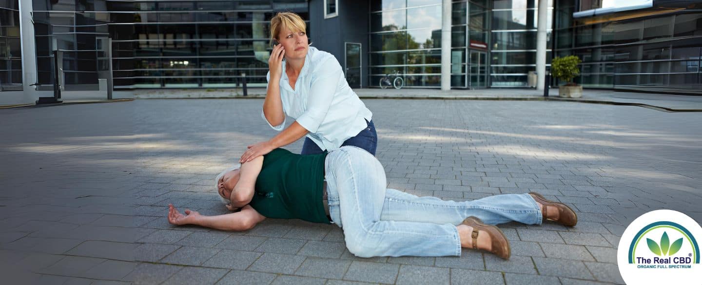 Femme appelant à l'aide pour une personne au sol en train de faire une crise d'épilepsie