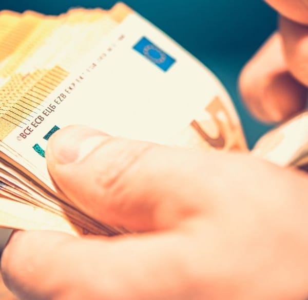 Mannelijke handen tellen een stapel eurobiljetten