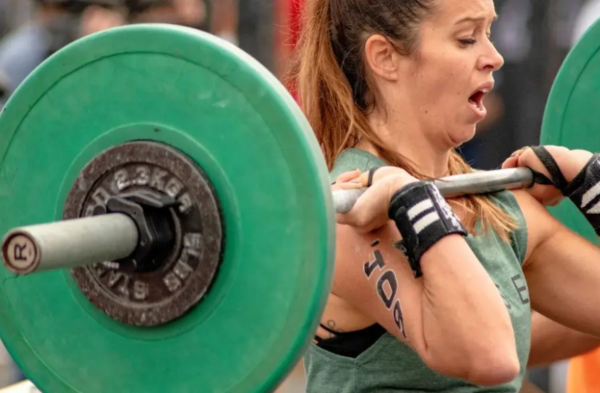 Vrouw die een barbell overhead tilt