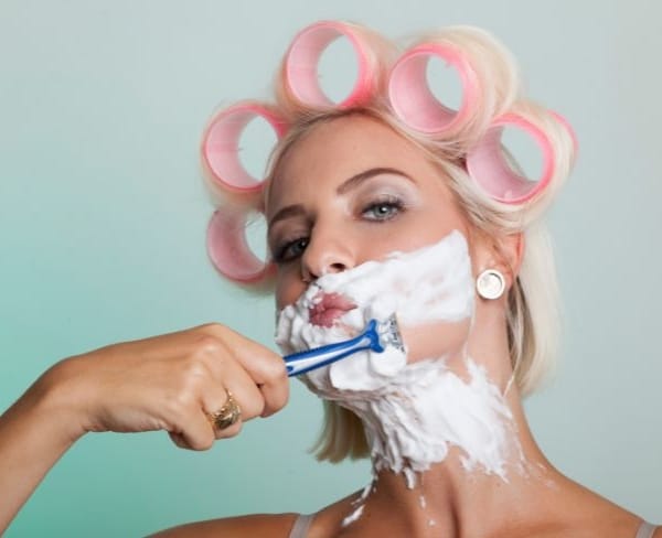 Vrouw met krulspelden scheert haar baard