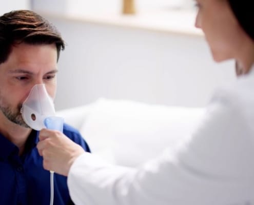 Man ademt in een zuurstofmasker vastgehouden door een arts