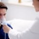 Mann atmet in eine von einem Arzt gehaltene Sauerstoffmaske
