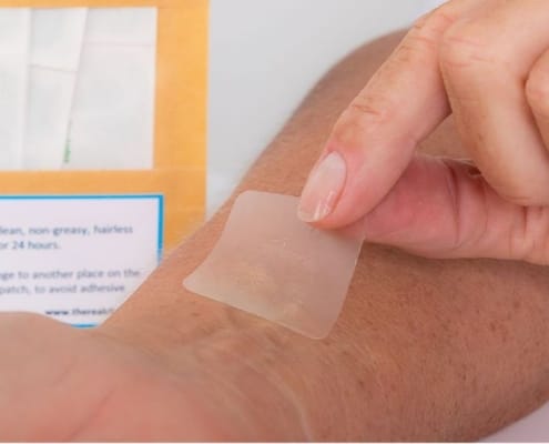 Person putting a CBD pain patch on her arm