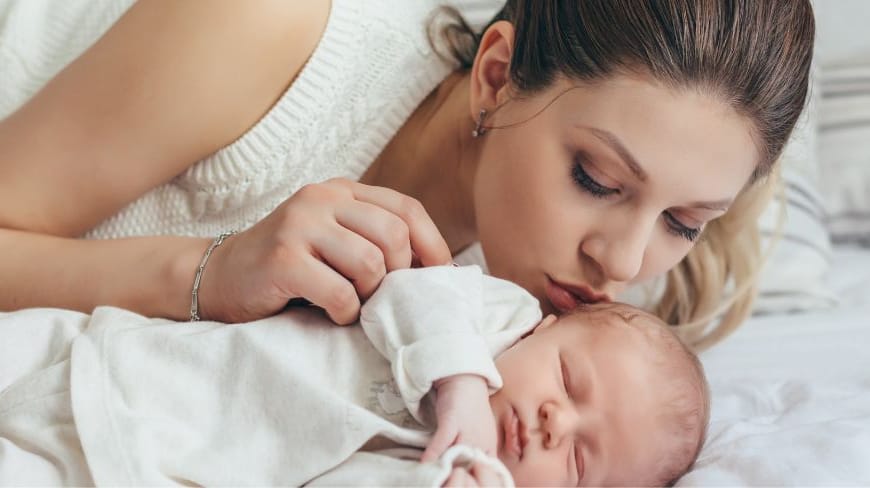 Neue Mutter küsst ihr Baby