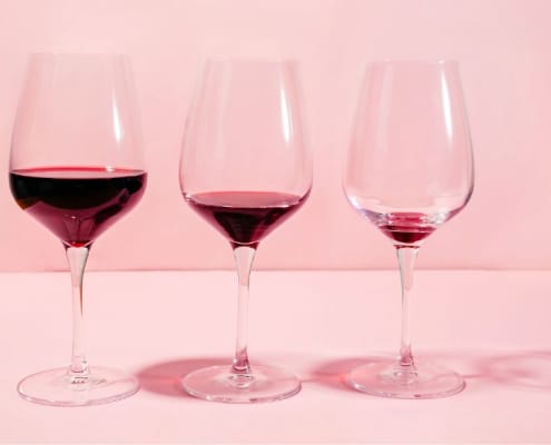Une rangée de verres à vin contenant de moins en moins de vin rouge