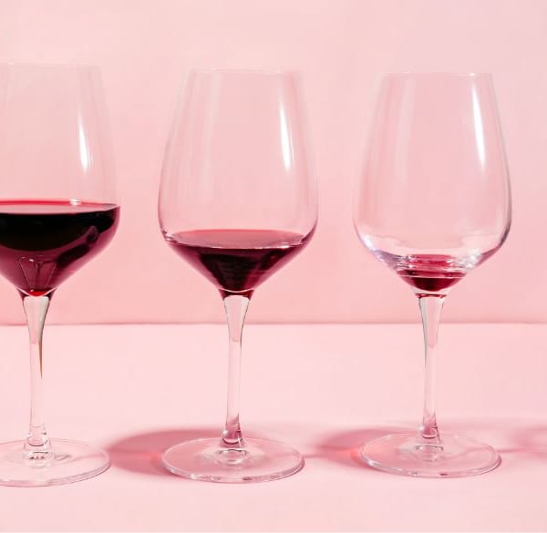 Eine Reihe von Weingläsern mit immer weniger Rotwein darin