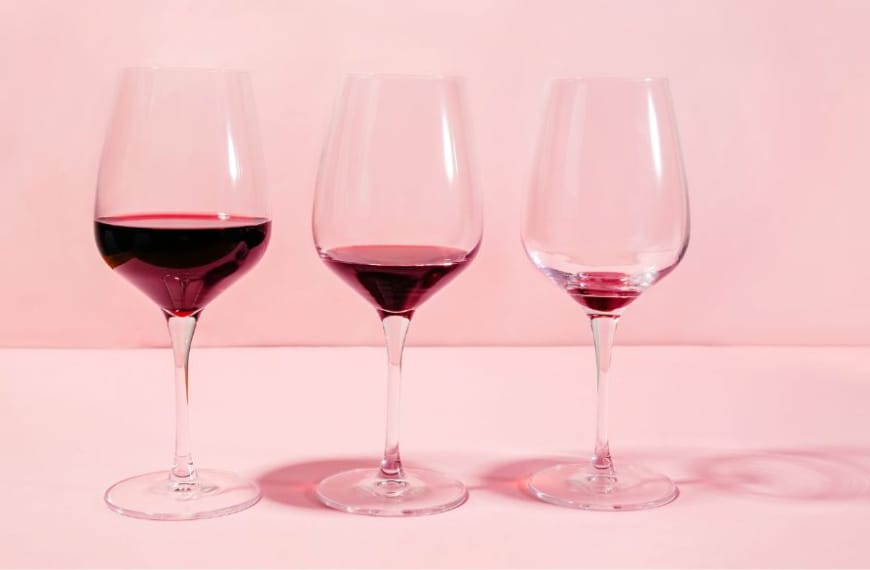 A row of wine glasses with less and less redwine in