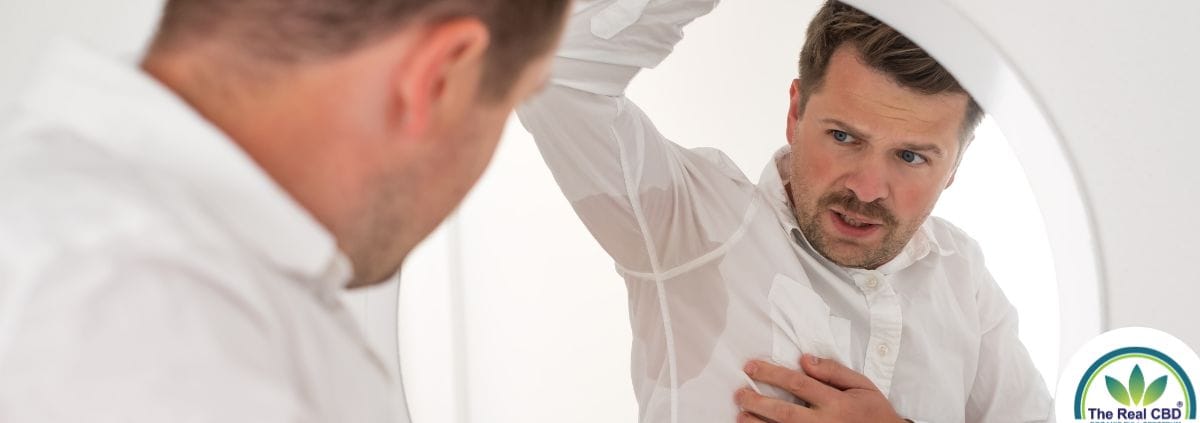 Man kijkt naar zijn bezwete oksels in de spiegel