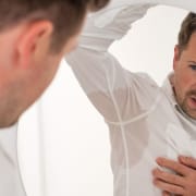 De-echte-CBD-voor-hyperhidrose Man kijkt naar zijn bezwete oksels in de spiegel