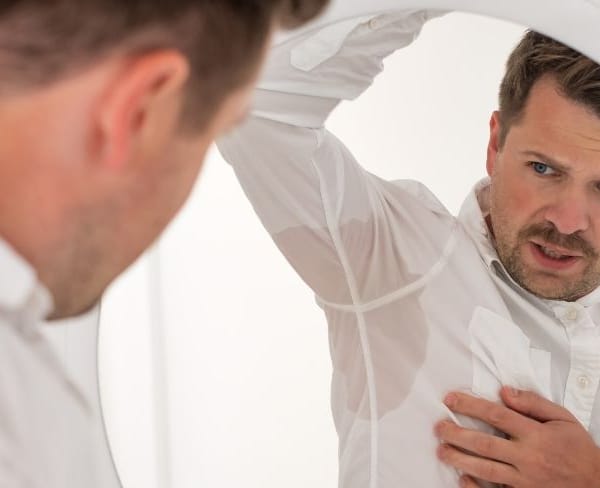Man looking at his sweaty armpits in the mirror