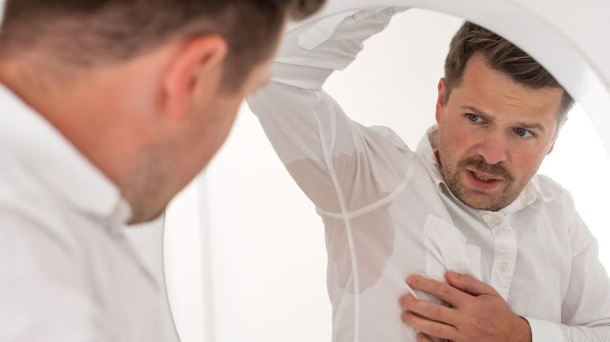 Man looking at his sweaty armpits in the mirror