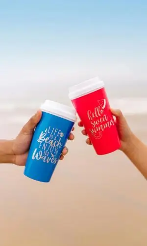 Two people cheering with plactic cups on the beach