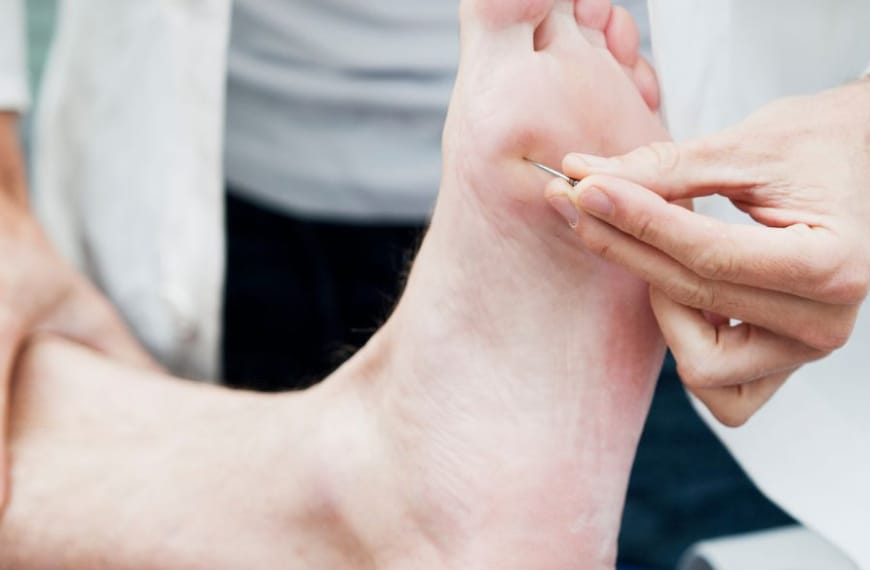 Doctor testing nerve reaction under a patients foot