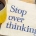 Coffee cup on a pc of paper saying OVERSTHINKING