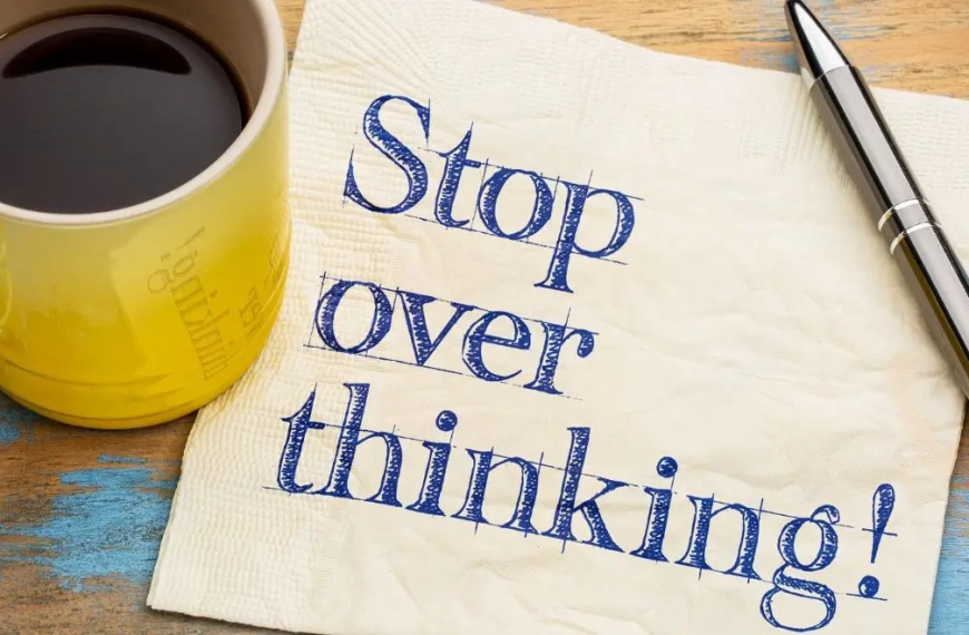 Coffee cup on a pc of paper saying OVERSTHINKING