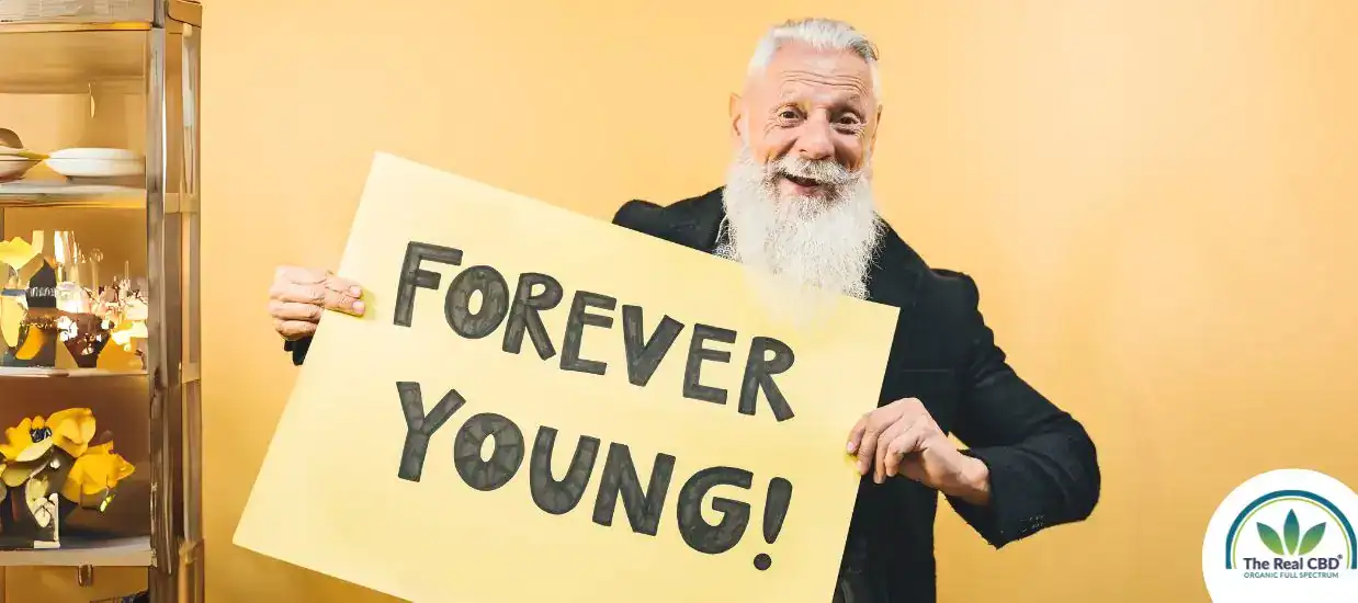 Older man looking happy holding a sign saying FOREVER YOUNG