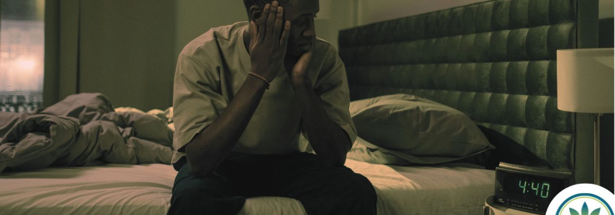 Man sitting on the edge of his bed at nighttime unable to sleep