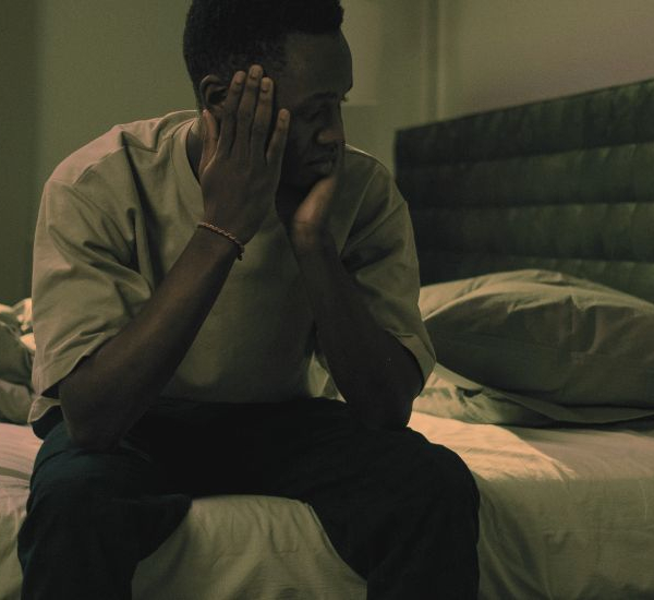 Man sitting on the edge of his bed at nighttime unable to sleep