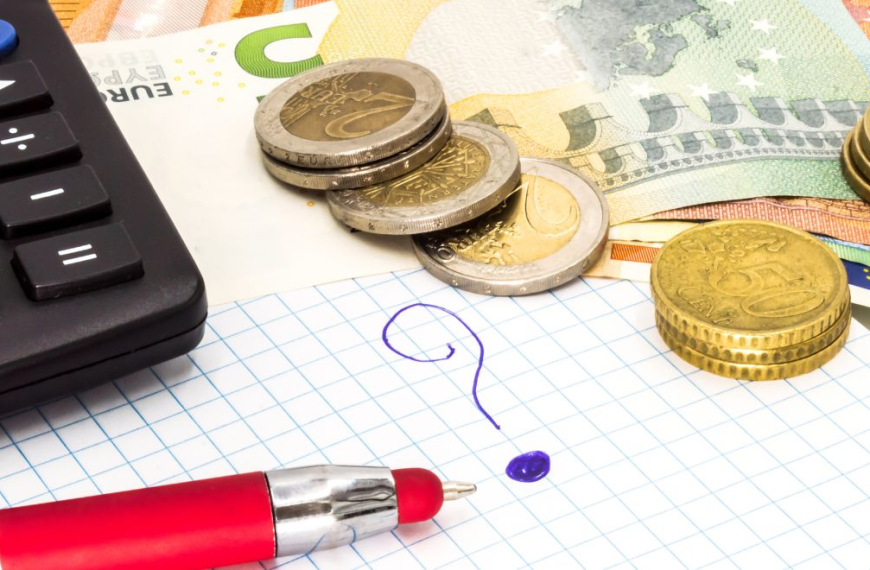 Calculator, money and a pen on top of a map