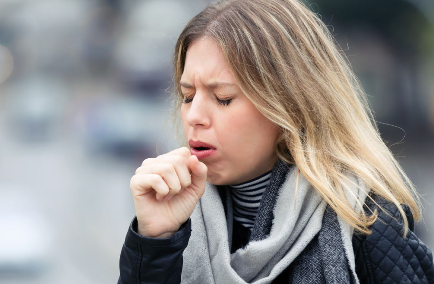 Woman coughing heavily into her hand