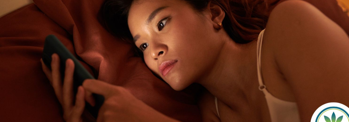 Woman laying in bed at night scrolling on her phone