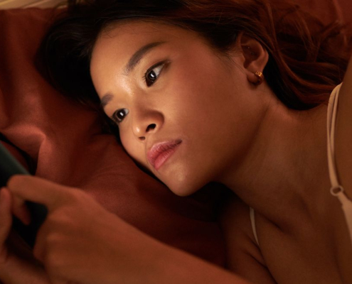 Woman laying in bed at night scrolling on her phone