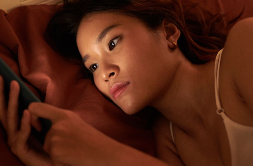 Woman laying in bed at night scrolling on her phone