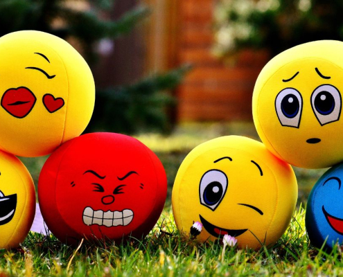Different moods emoji balls on a green lawn