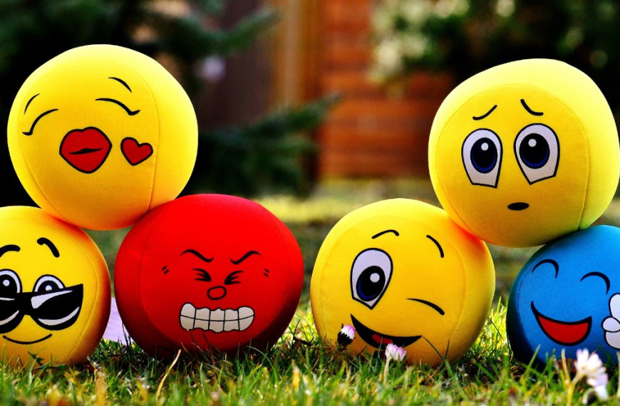 Different moods emoji balls on a green lawn