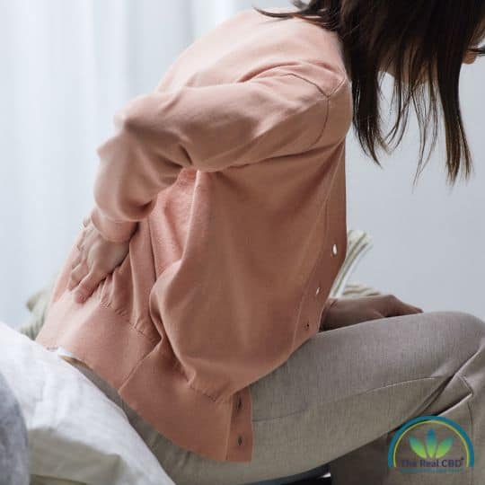 Woman with lowerback pain sitting on a bed