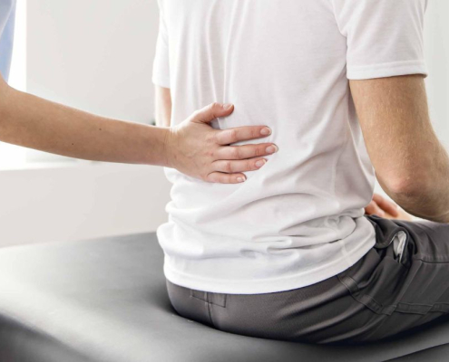 Fysio holding the lower back of a man in pain