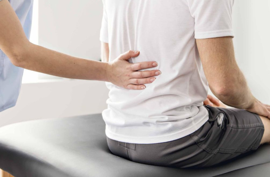Fysio holding the lower back of a man in pain