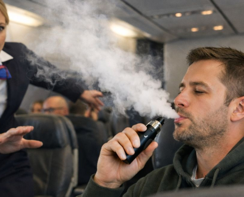 Flight attendant stopping a man smoking a vape on a plane