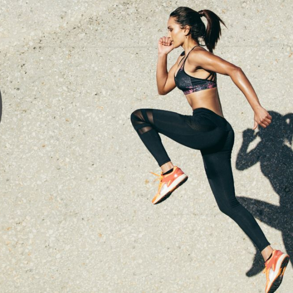 Woman and her shadow jumping infront of a wall clock
