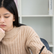 Girl sitting at a work table looking tired and anxious