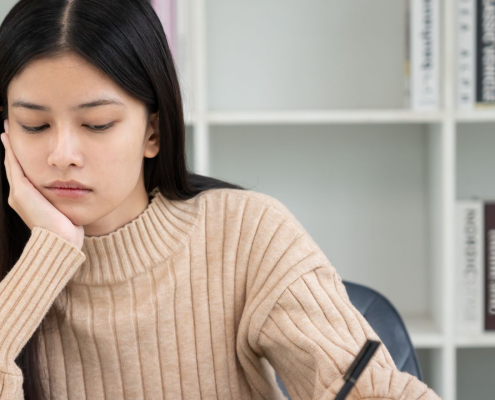 Girl sitting at a work table looking tired and anxious