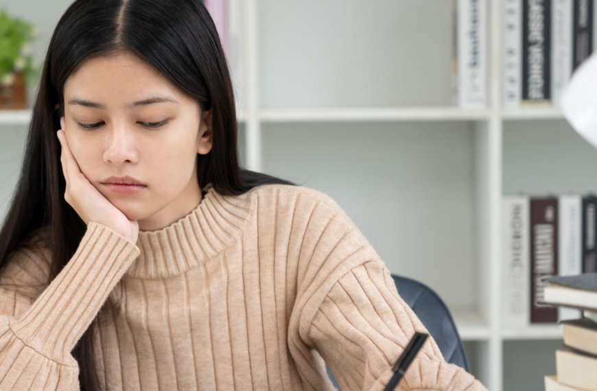Girl sitting at a work table looking tired and anxious