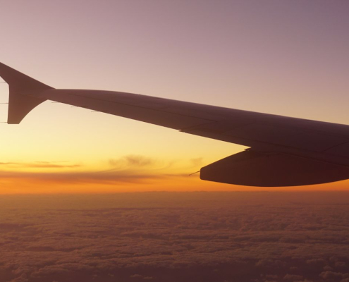 Wing of an aeroplane flying into a sunrise