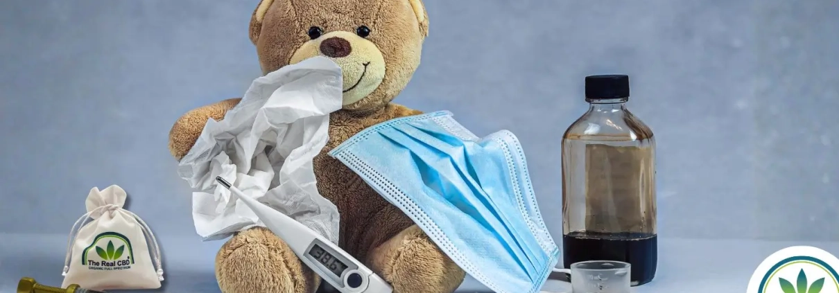 Cough medicine and CBD oil standing next to a teddy bear